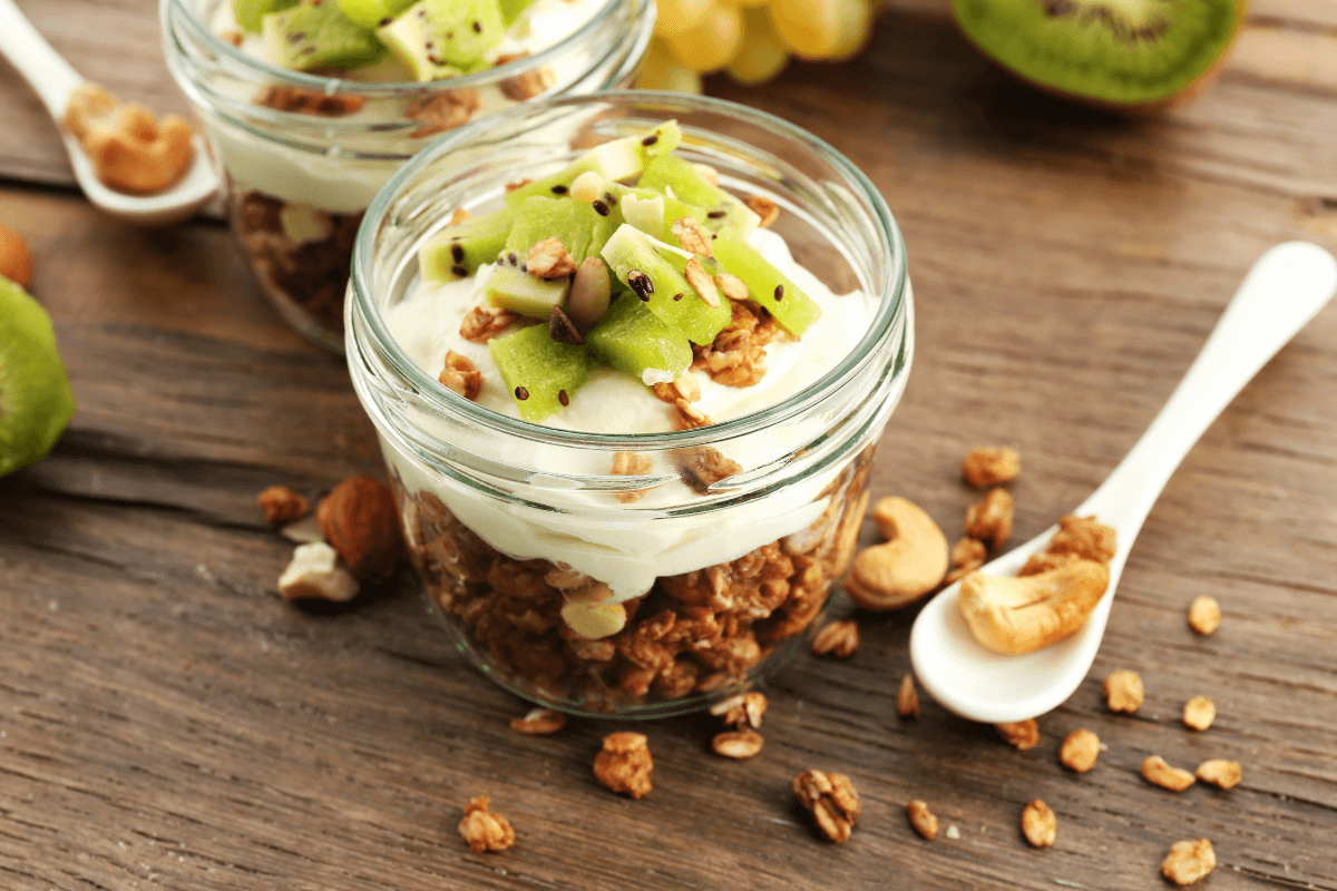 Schichtjoghurt im Glas mit Granola, Joghurt und frischen grünen Apfelstücken, dekoriert mit Nüssen.