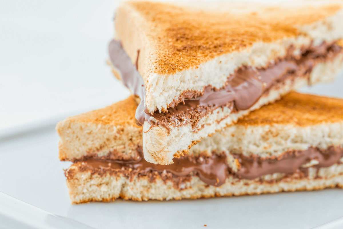 Zwei halbierte, getoastete Sandwiches mit geschmolzener Kinderschokolade zwischen den Brotscheiben.