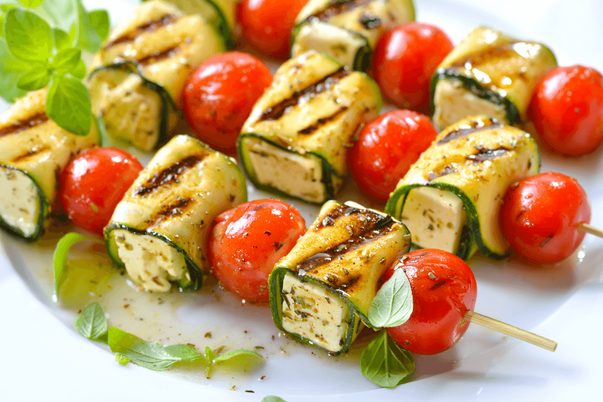 Gegrillte Zucchini-Feta-Spieße mit Kirschtomaten, garniert mit frischen Kräutern.