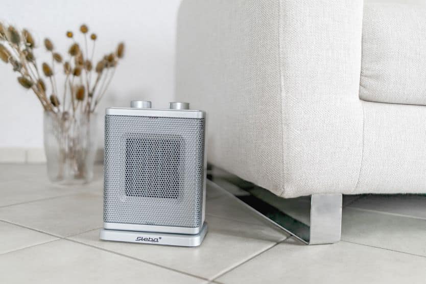 Kompakter Heizlüfter von Steba, silberfarben, neben einem beigen Sofa, ideal für effiziente Raumerwärmung.