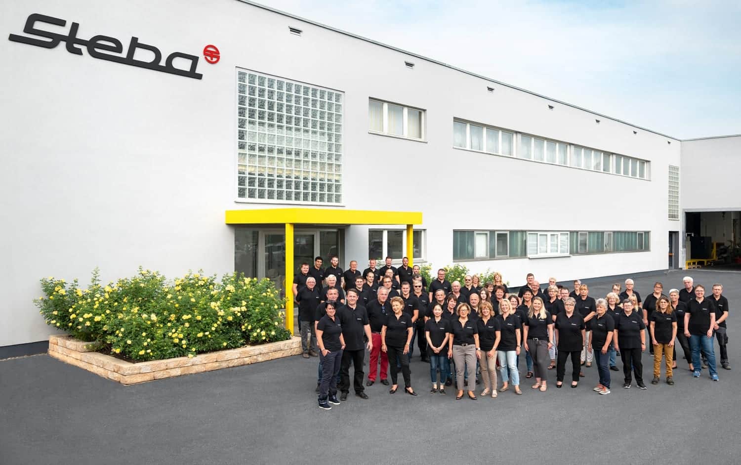 Gruppenfoto der Steba-Mitarbeiter vor dem Firmengebäude, das zur Feier von 100 Jahren Steba aufgenommen wurde.