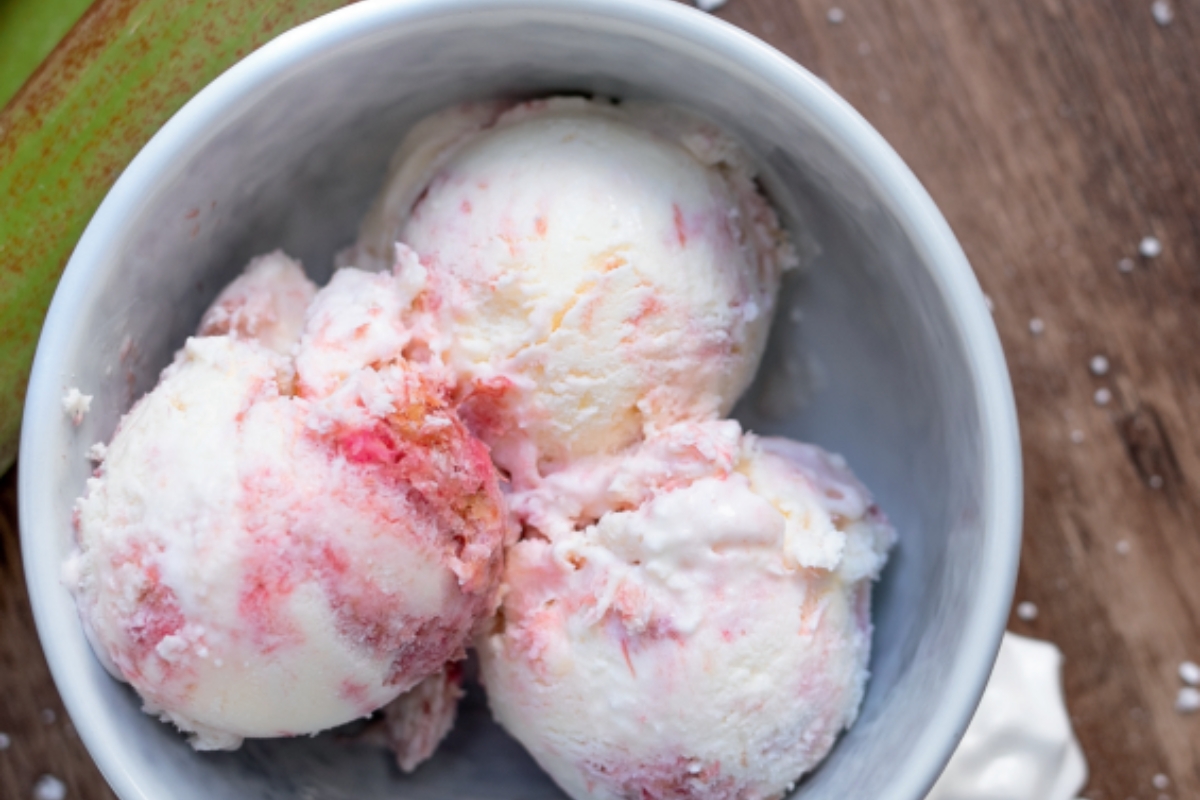 Eine Schale mit Rhabarber-Baiser Eis, bestehend aus cremigen, rosa-weißen Eiskugeln.