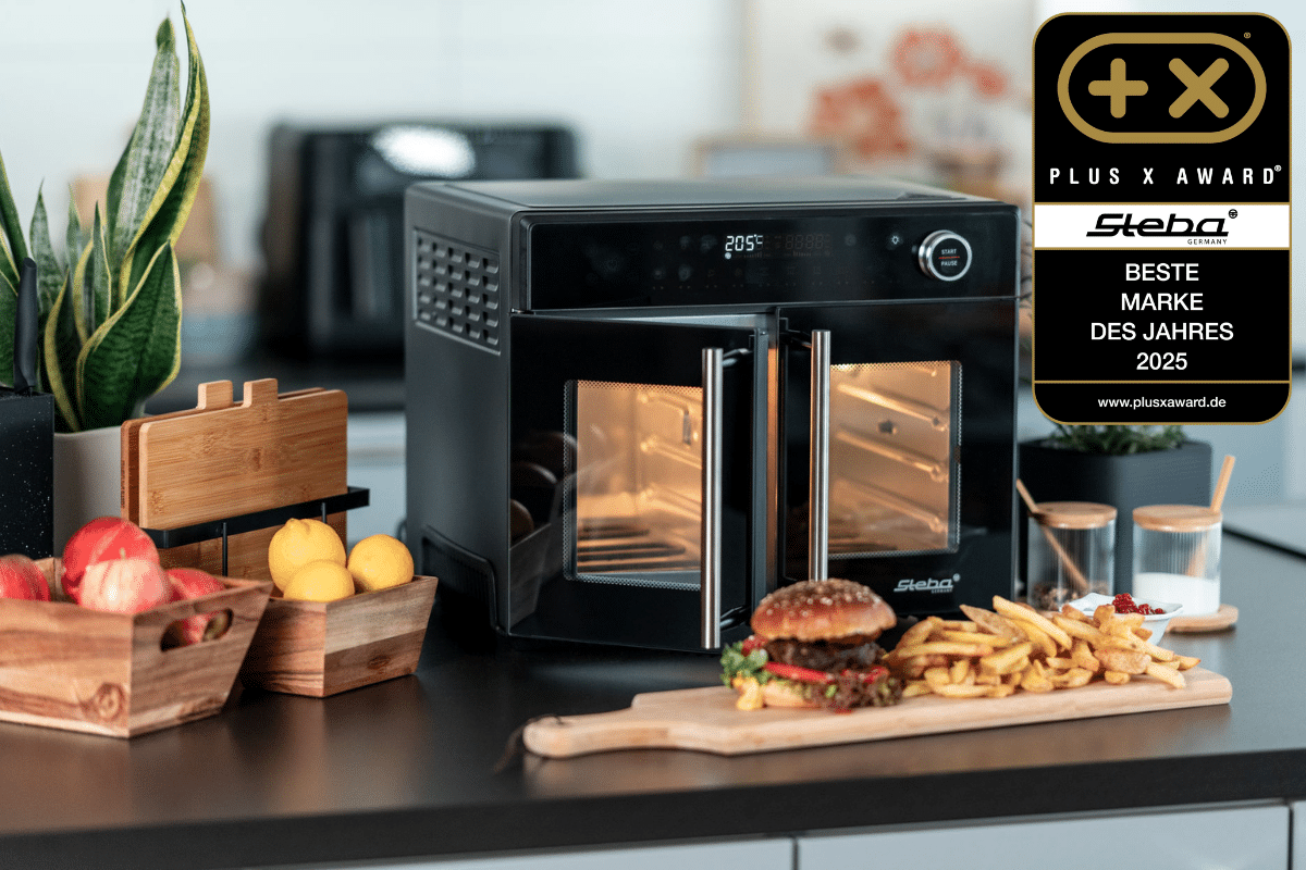 Steba Elektrogerät mit zwei Türen, Award-Auszeichnung, umgeben von frischen Lebensmitteln und Küchenutensilien.