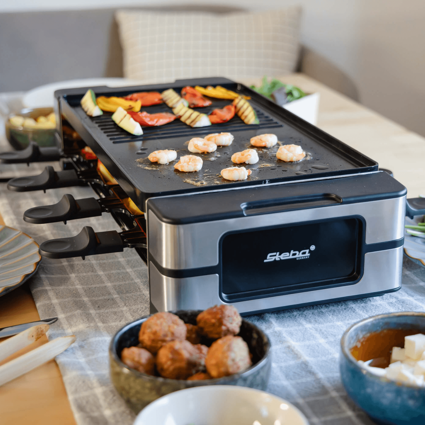 Steba Raclette Grill RC180 mit Grillfläche, Garnelen und Gemüse. Ideal für geselliges Kochen am Tisch.